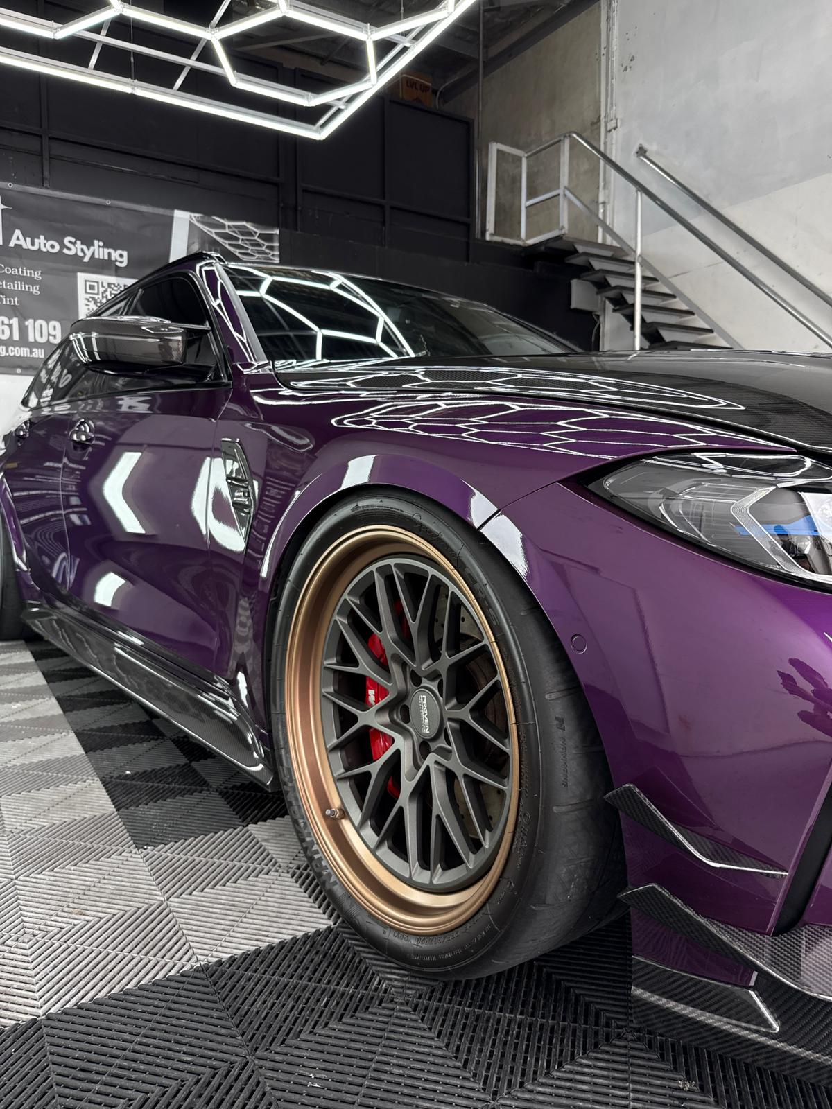 Purple BMW M3 with bronze BBS wheels close-up at A1 Auto Styling, ceramic coated paint reflecting the hexagonal LED ceiling